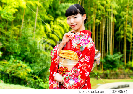 A Japanese woman wearing a furisode kimono standing in a bamboo forest 132086841