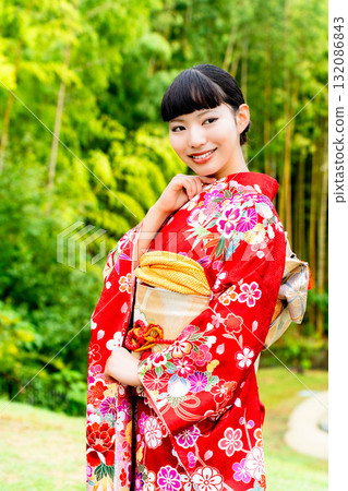 A Japanese woman wearing a furisode kimono standing in a bamboo forest 132086843