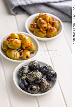 Tapas. Flavored pickled olives in bowl on white table. 132087233