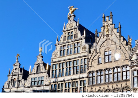 Guildhalls on Grote Markt in Antwerp, Belgium, featuring traditional step gables and golden statues under a clear blue sky. 132087645
