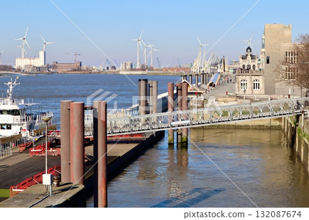 Scheldt river with ferry pier, gangway, and wind turbines, Antwerp port industrial landscape. Belgium 132087674