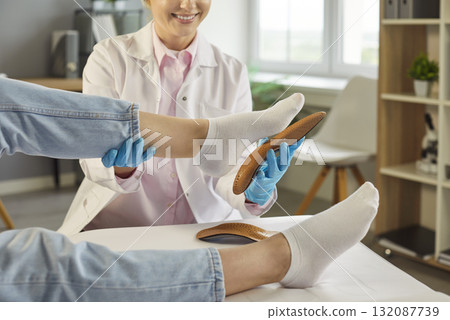 Orthopedist examines patient foot in clinic, fitting inserts for posture and care Orthopedist examines patient foot in clinic, fitting inserts for posture and care 132087739