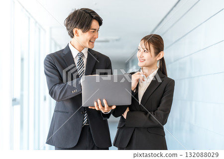 Young Asian businessmen and women in suits standing in an office corridor Young Asian businessmen and women in suits standing in an office corridor 132088029