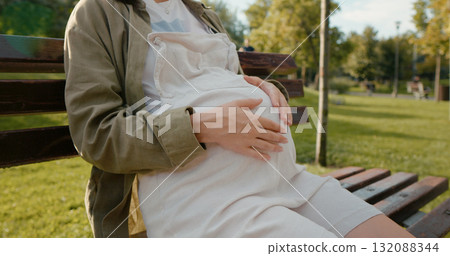 Pregnant belly touching and relaxing in the park. 132088344
