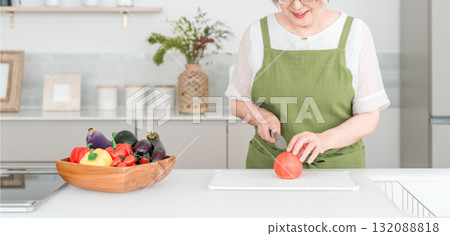 A senior Asian woman with gray hair cooking in her home kitchen. A senior Asian woman with gray hair cooking in her home kitchen. 132088818