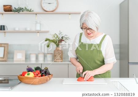 A senior Asian woman with gray hair cooking in her home kitchen. A senior Asian woman with gray hair cooking in her home kitchen. 132088819
