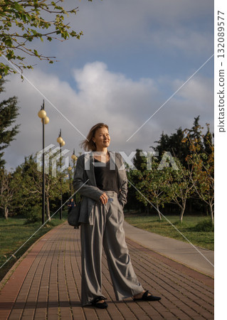 Woman Suit Park, Standing Fashionable Woman in Grey Suit on Pathway in Park, Fashionable Woman in Grey Suit Woman Suit Park, Standing Fashionable Woman in Grey Suit on Pathway in Park, Fashionable Woman in Grey Suit 132089577