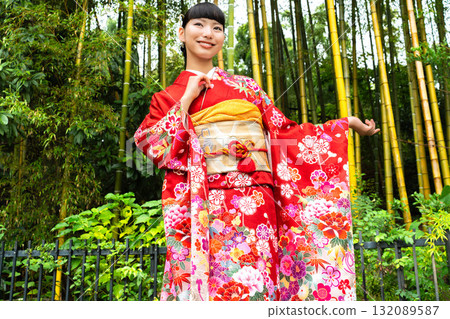 A Japanese woman wearing a furisode kimono standing in a bamboo forest 132089587