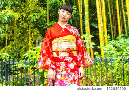 A Japanese woman wearing a furisode kimono standing in a bamboo forest 132089590