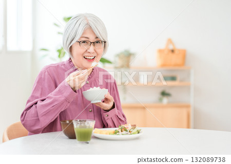 A gray-haired senior woman eating in the dining room at home A gray-haired senior woman eating in the dining room at home 132089738