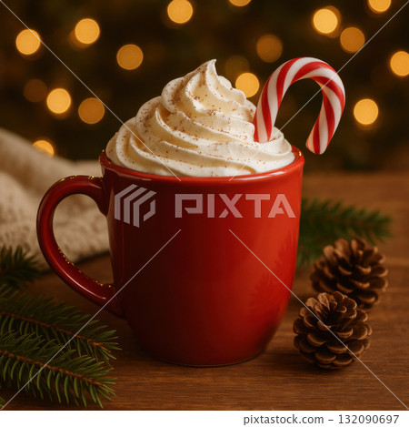 Red mug of hot chocolate with whipped cream and candy cane on cozy Christmas table setting. warm fairy lights background creates lovely holiday comfort mood 132090697