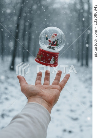 Magic snow globe with Santa floating above a hand in winter forest 132090945
