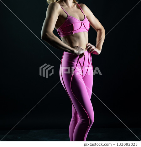 athletic female body in pink sportswear on dark background, fitness woman, athletic girl torso 132092023