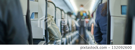 Passengers seated inside airplane cabin wearing masks with caucasian and asian 132092600