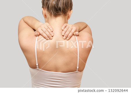 Caucasian female adult with neck and shoulder pain in white tank top facing 132092644