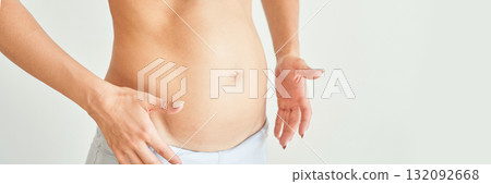 Female adult caucasian holding belly in white underwear on neutral background 132092668
