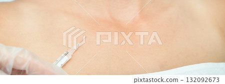 Close-up of needle injecting botox into female caucasian skin on chest 132092673