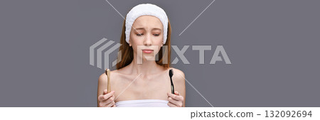 Young caucasian female contemplating toothbrush choice with bath headband Young caucasian female contemplating toothbrush choice with bath headband 132092694