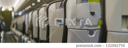 Empty airplane cabin interior with rows of seats and overhead compartments 132092750