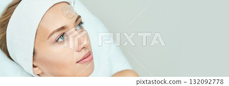 Young caucasian female receiving facial treatment with hydrogel patch in spa 132092778