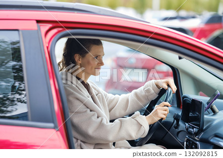 Woman driving a red car in a parking lot, showing focus and readiness on a busy day 132092815
