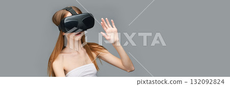 Young caucasian female exploring virtual reality with vr headset on gray 132092824