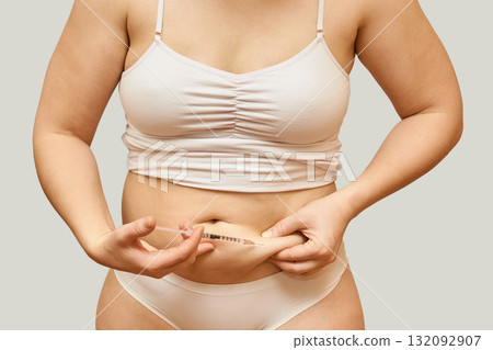 Adult female injecting medication in abdomen for health management wearing Adult female injecting medication in abdomen for health management wearing 132092907