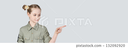 Caucasian young girl in green shirt pointing right with focused expression Caucasian young girl in green shirt pointing right with focused expression 132092920