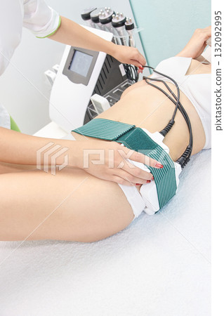Female receiving body contouring treatment with cavitation machine in modern spa Female receiving body contouring treatment with cavitation machine in modern spa 132092995