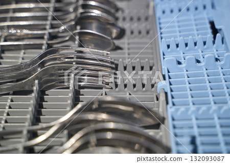 Close up of forks and spoons neatly arranged in dishwasher silverware basket 132093087