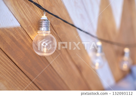 String of hanging edison bulb lights with warm glow on wooden chevron patterned String of hanging edison bulb lights with warm glow on wooden chevron patterned 132093112