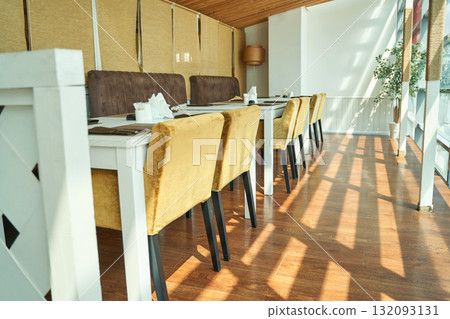 Sunlit modern restaurant interior with elegant yellow chairs and white tables Sunlit modern restaurant interior with elegant yellow chairs and white tables 132093131