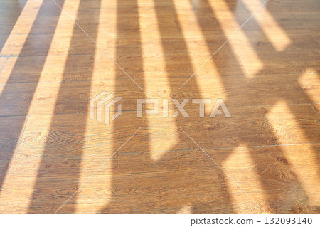 Sunlight streaming through window creating patterns on wooden floor 132093140