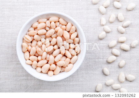 Cooked white beans, in a white bowl on linen. Boiled and canned cannellini beans, preserved white kidney beans, a variety of the common bean, Phaseolus vulgaris, and a vegetarian staple food. Photo 132093262