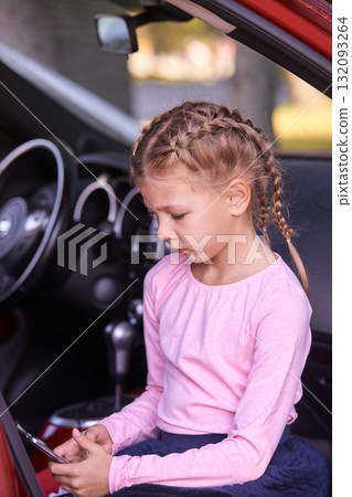 Caucasian young girl with braids sitting in car with smartphone focused 132093264
