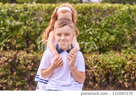 Young caucasian kids playing outdoors in summer garden with green hedges 132093370