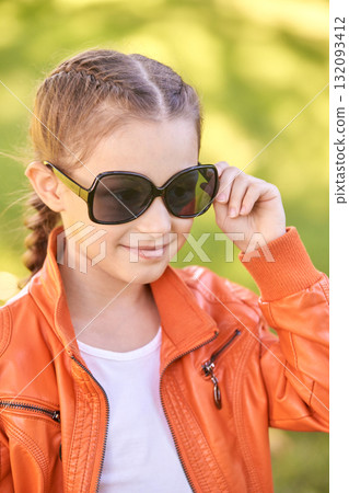 Young caucasian female child in orange jacket wearing sunglasses outdoors 132093412