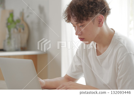 在客廳裡的計算機上工作的年輕人 132093446