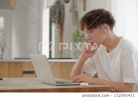 在客廳裡的計算機上工作的年輕人 在客廳裡的計算機上工作的年輕人 132093451