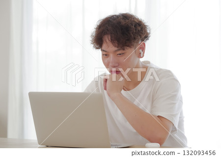 在客廳裡的計算機上工作的年輕人 在客廳裡的計算機上工作的年輕人 132093456