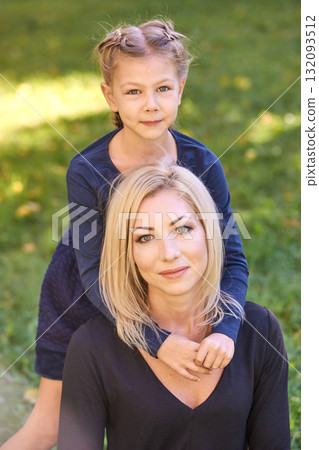 Caucasian female child with blonde adult woman smiling in outdoor park setting 132093512