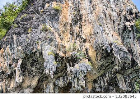 Limestone cliff with natural erosion and vegetation in sunlit landscape 132093645