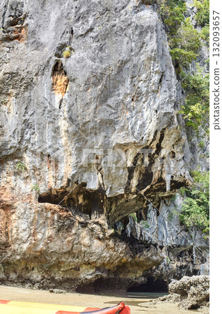 Rugged coastal cliff with eroded rock formations and vegetation in natural 132093657