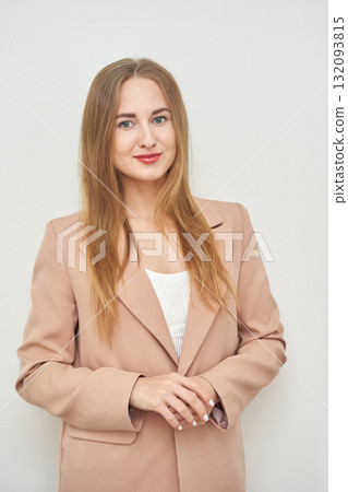 Young caucasian female in business attire smiling confidently against plain back Young caucasian female in business attire smiling confidently against plain back 132093815