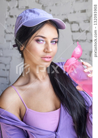 Young asian woman in purple outfit with pink water bottle against brick wall Young asian woman in purple outfit with pink water bottle against brick wall 132093908
