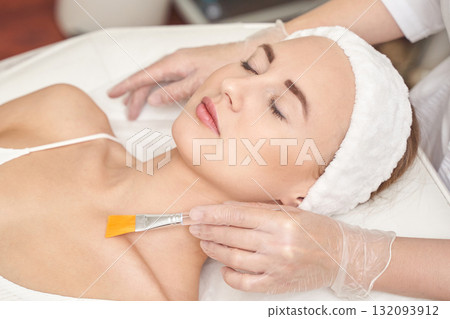 Female adult caucasian receiving facial mask treatment at spa with relaxed 132093912