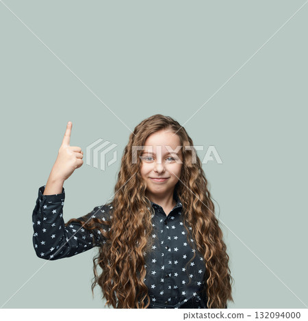 Smiling caucasian female child with long curly hair pointing upward in starry 132094000