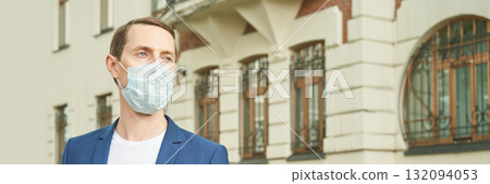 Caucasian male adult in blue suit wearing face mask outdoors near historic 132094053