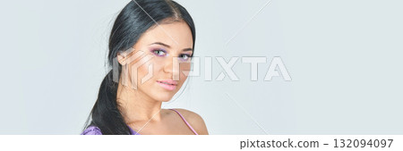 Young hispanic woman with long black hair in lavender top looking at camera 132094097