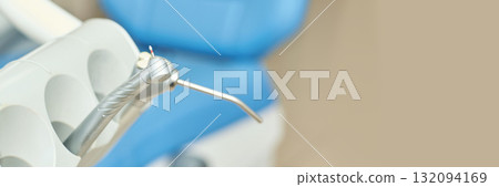Close-up of dental handpiece in modern clinic with blue dental chair Close-up of dental handpiece in modern clinic with blue dental chair 132094169